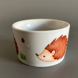 White bowl with hedgehog illustration on a grey background